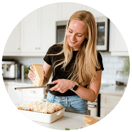 Ashley standing in the kitchen shredding cheese.